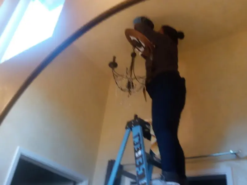 Electrician installing a chandelier in a Wilmer residence